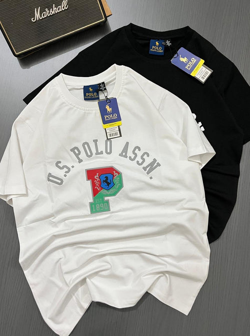 White and black t-shirts with U.S. Polo Assn. branding on a gray surface.